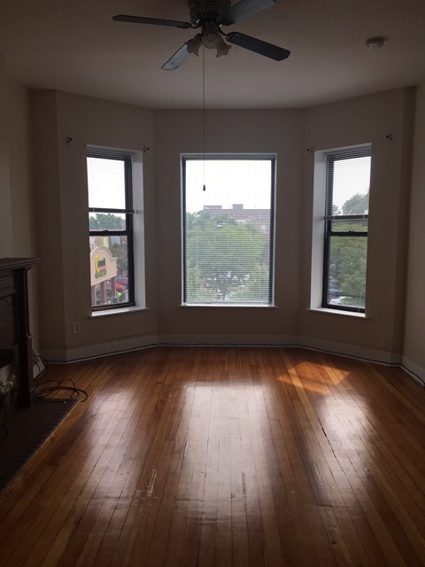 an empty living room with wood floors and three windows