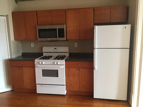 an empty kitchen with white appliances and wooden cabinets