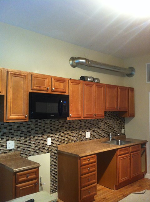 a kitchen with wooden cabinets and a black microwave