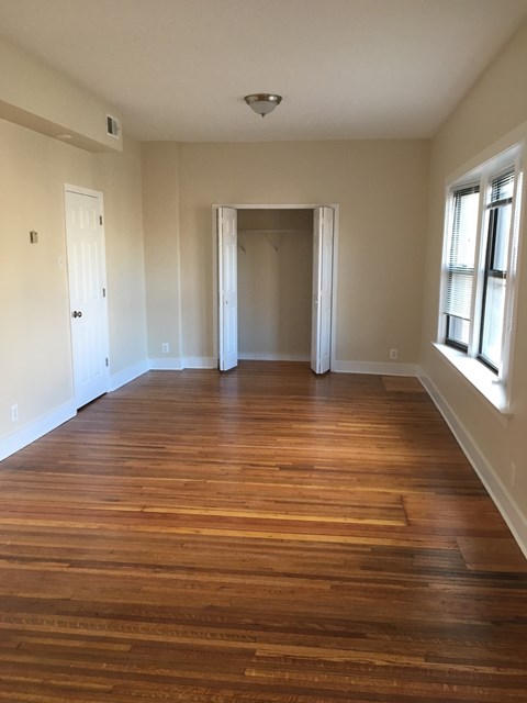 an empty living room with wooden floors and a window