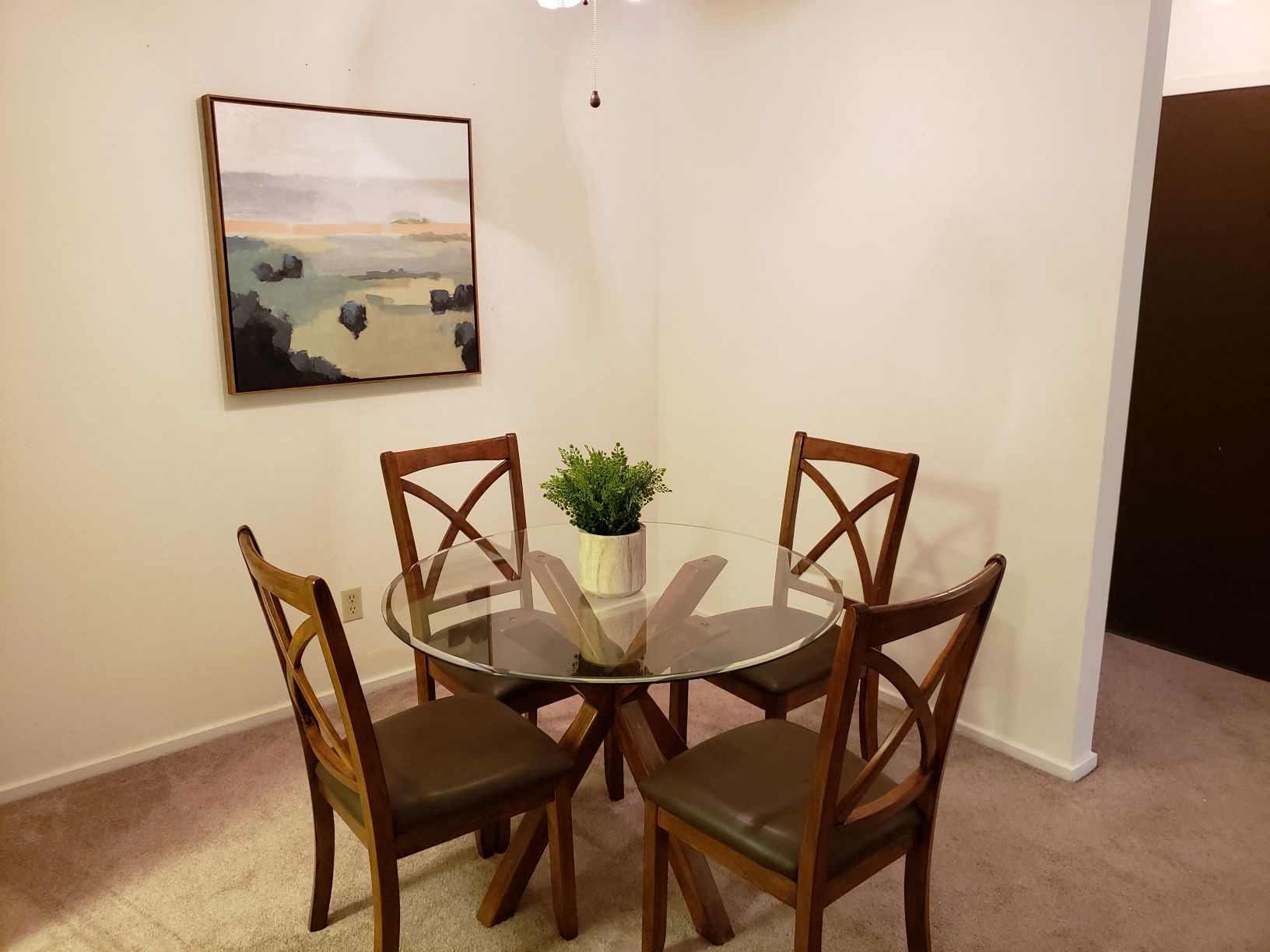 a dining room table with chairs and a painting on the wall