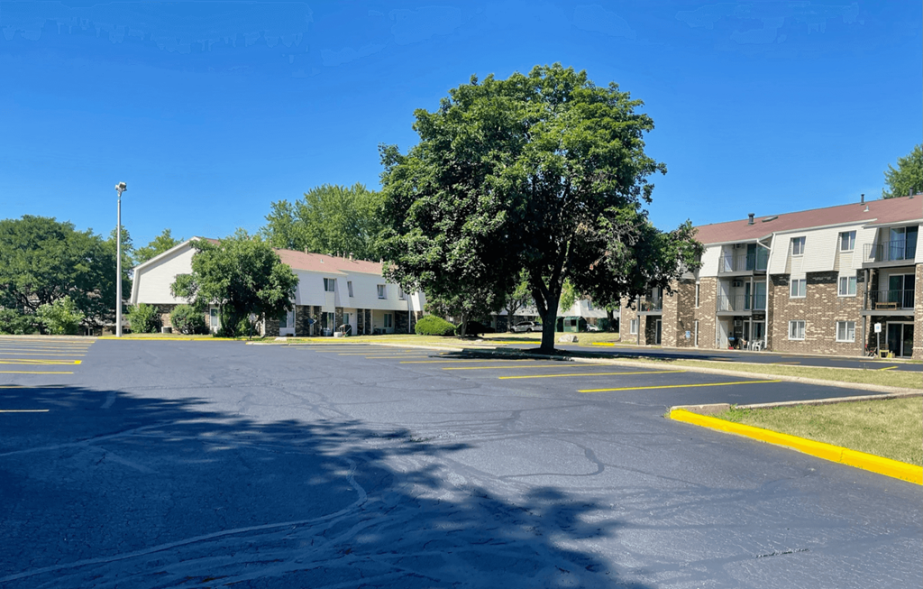 an empty street in front of an apartment building with a tree
