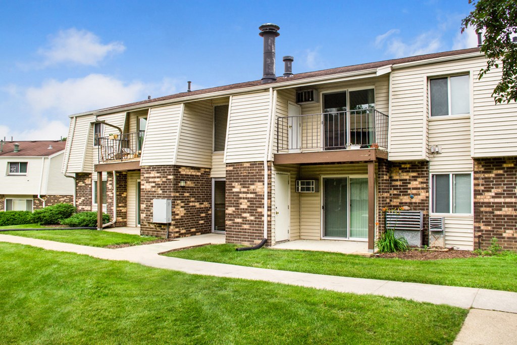 the view of a apartment building with a sidewalk and grass