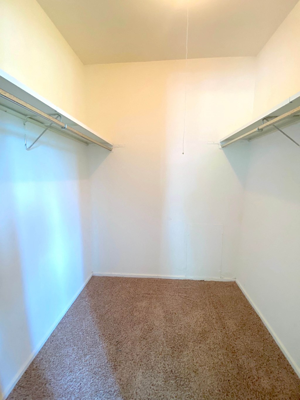 a room with white walls and a carpet and two sliding closet doors