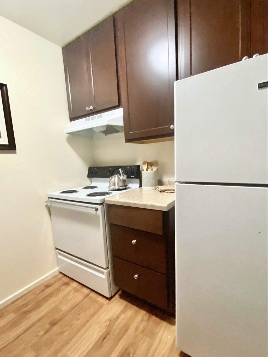 a kitchen with white appliances and brown cabinets and a refrigerator