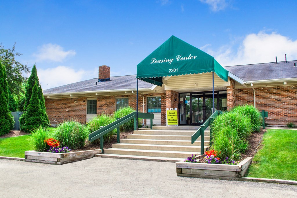the front of a brick building with a green awning and stairs