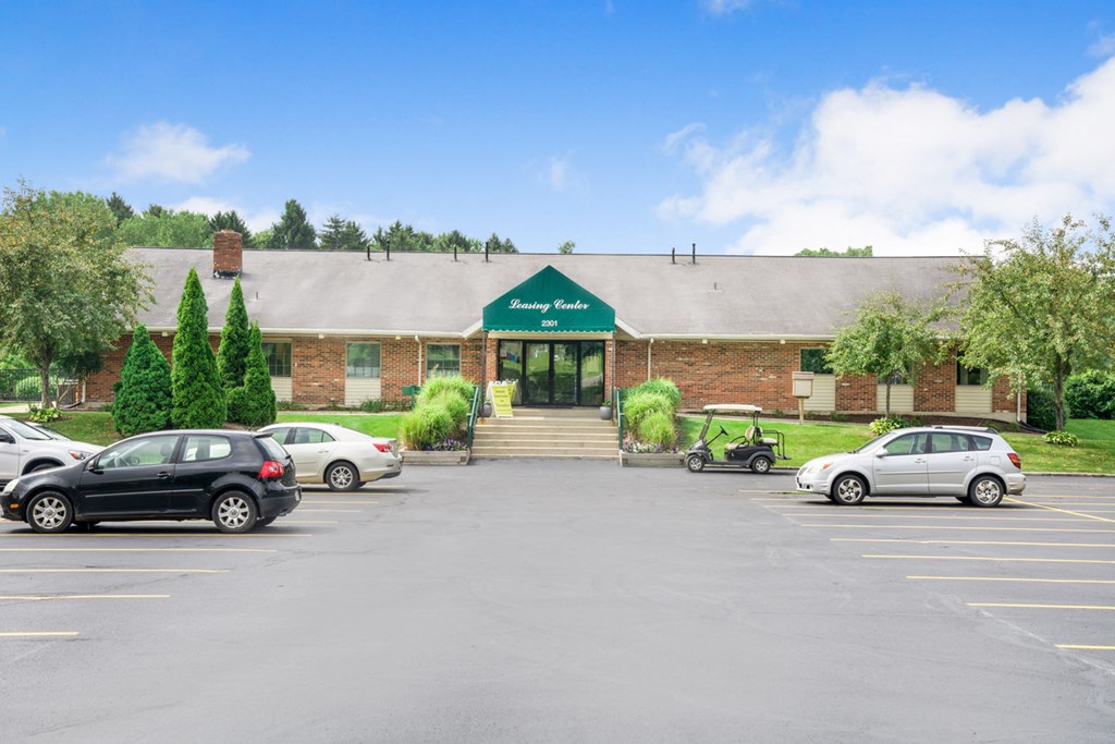 a parking lot in front of a brick building with cars parked