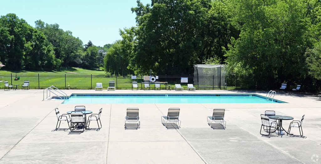a swimming pool with chairs and tables around it