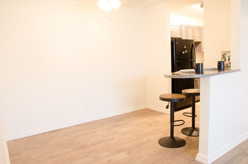 a kitchen with a bar with stools and a refrigerator