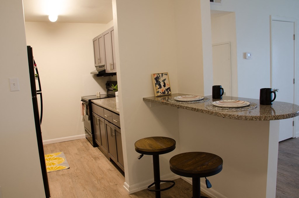 a kitchen with a counter with two stools and a sink