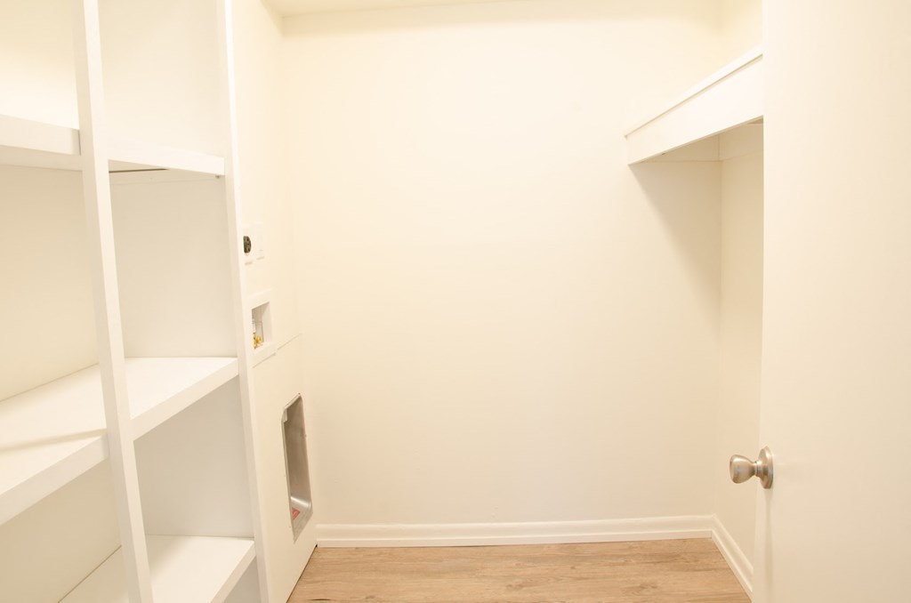 a room with white shelves and a closet and a door