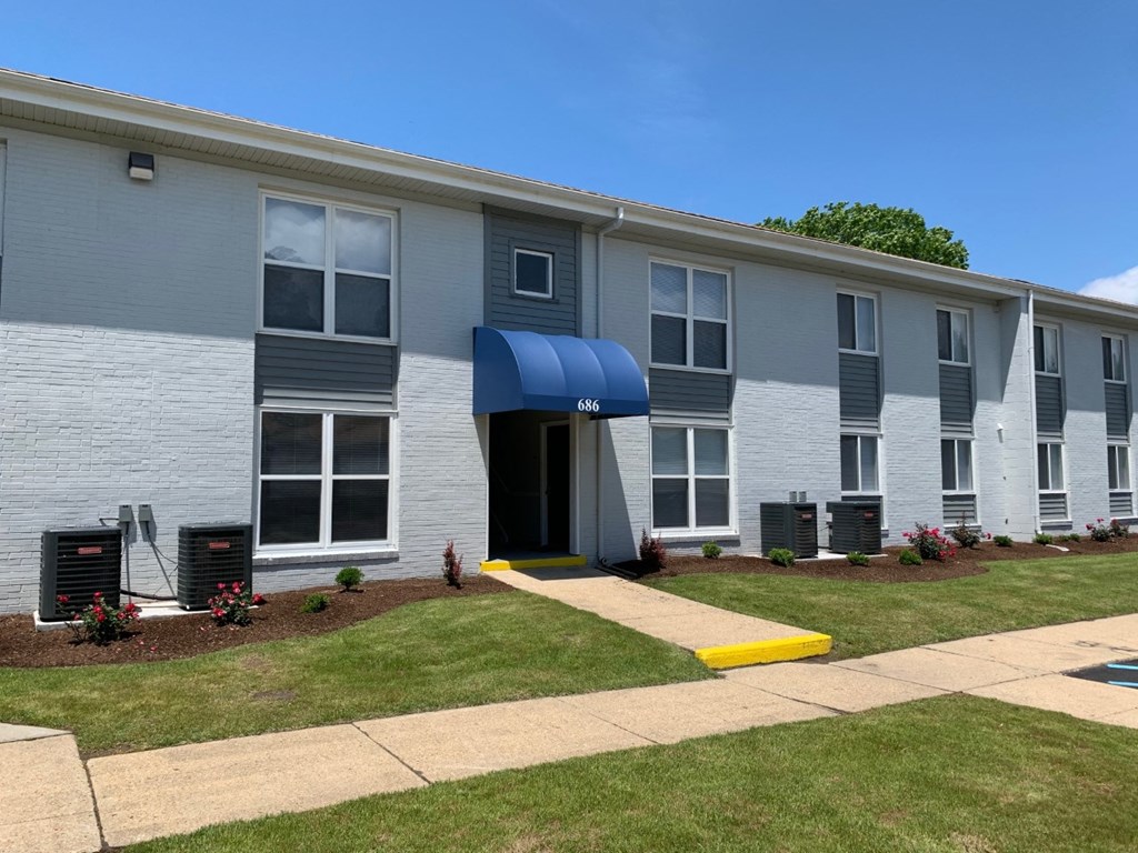 an apartment building with a blue awning and grass