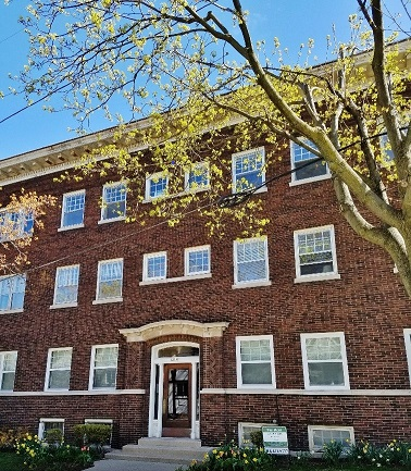 a red brick building with a tree in front of it