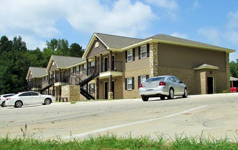 A white car is parked in front of a two-story house.