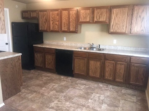 A kitchen with wooden cabinets and a black refrigerator.