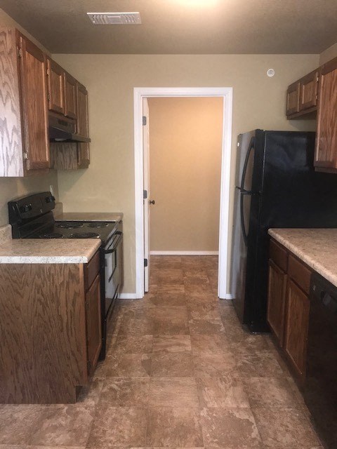 A kitchen with a black fridge and wooden cabinets.