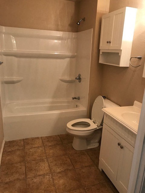 A white toilet with a white bathtub and sink in a bathroom.