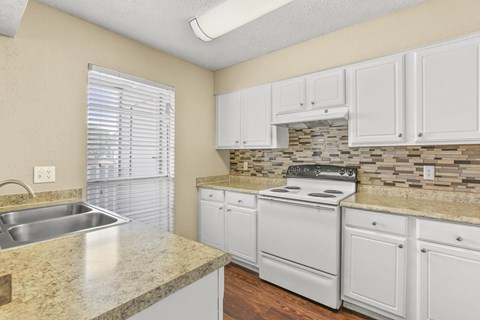 a kitchen with white cabinets and a sink and a stove