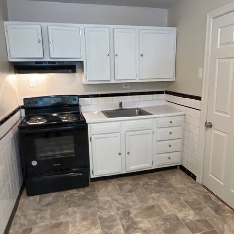 A black stove and oven in a kitchen with white cabinets.