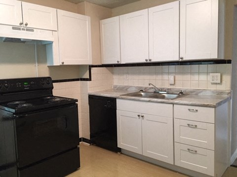 A kitchen with black appliances and white cabinets.