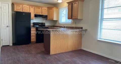 A kitchen with wooden cabinets and a black refrigerator.