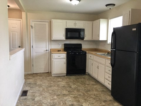 A kitchen with black appliances and white cabinets.
