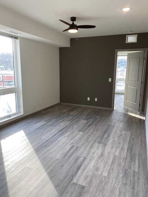 A room with a ceiling fan and light fixture, and a door leading to another room.