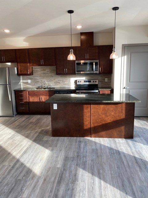 A kitchen with a wooden island and pendant lights.