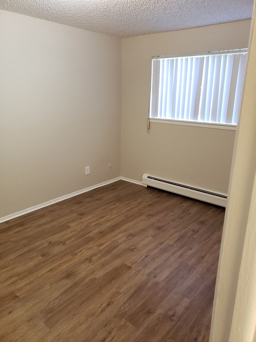 an empty room with wooden floors and a window