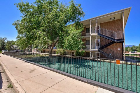A tree is in front of a two-story apartment building.
