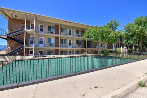 A multi-story apartment building with a pool in front.