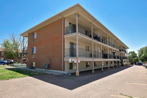 A multi-story apartment building with a parking lot in front.