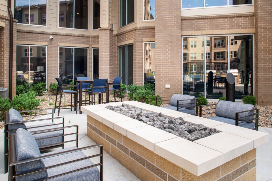 an outdoor seating area with a fire pit in front of a building
