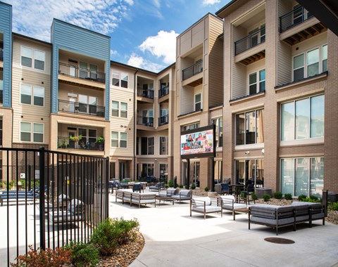 an outdoor area with benches and tables in front of an apartment building