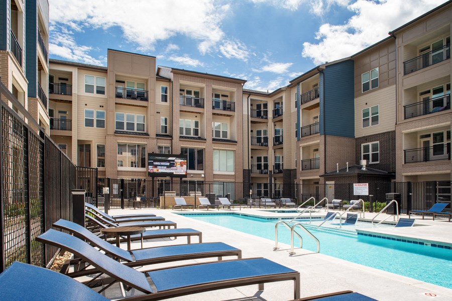 a swimming pool with lounge chairs in front of an apartment building