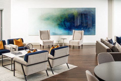 a living room with couches and chairs and a large painting on the wall