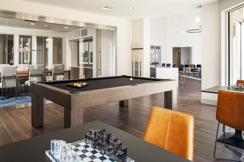 a billiards table in a living room with a bar and tables