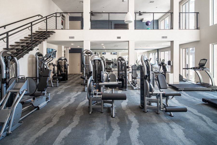 a gym with cardio equipment and a spiral staircase