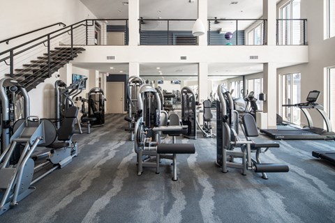 a gym with cardio equipment and a spiral staircase