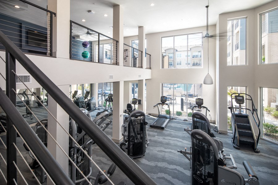 a gym with treadmills and weights in a building with large windows