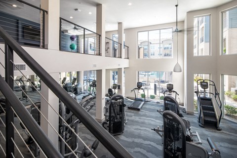 a gym with treadmills and weights in a building with large windows