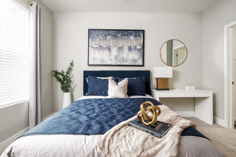 a bedroom with a bed with a blue comforter and pillows