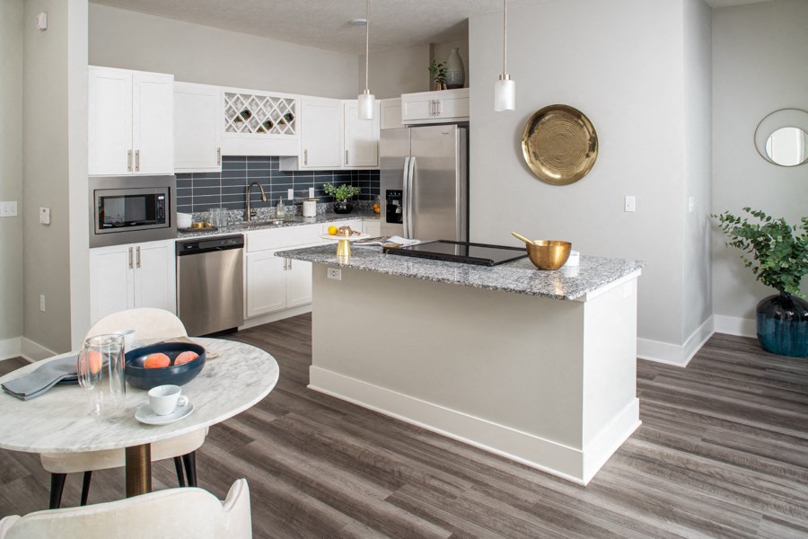 a kitchen with white cabinets and a marble counter top