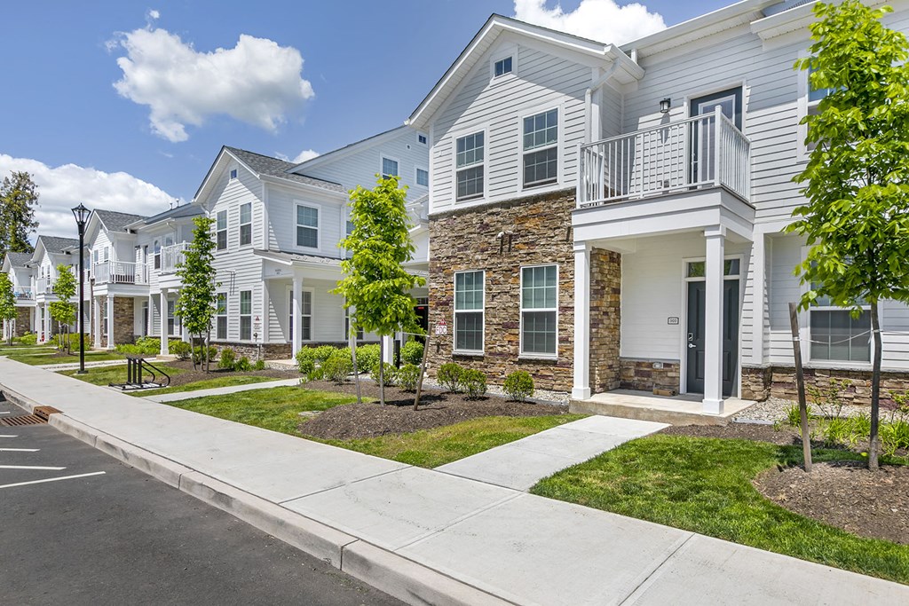 a row of white houses with a sidewalk and grass