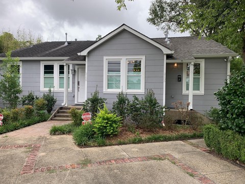 a gray house with green shutters and a stop sign