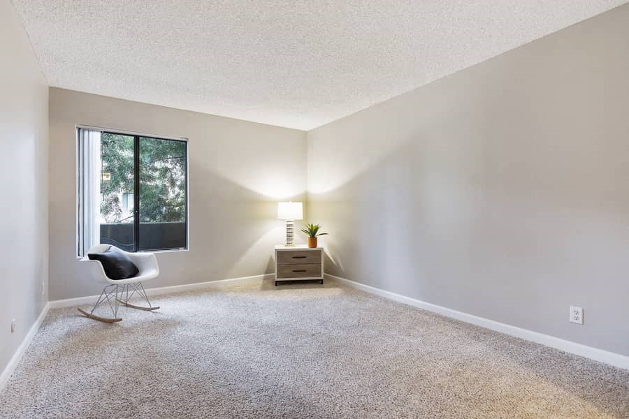 an empty living room with a chair and a window