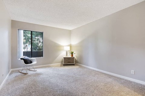 an empty living room with a chair and a window