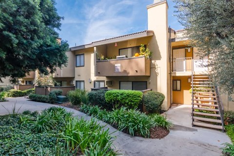 the outlook of an apartment building with stairs and a garden
