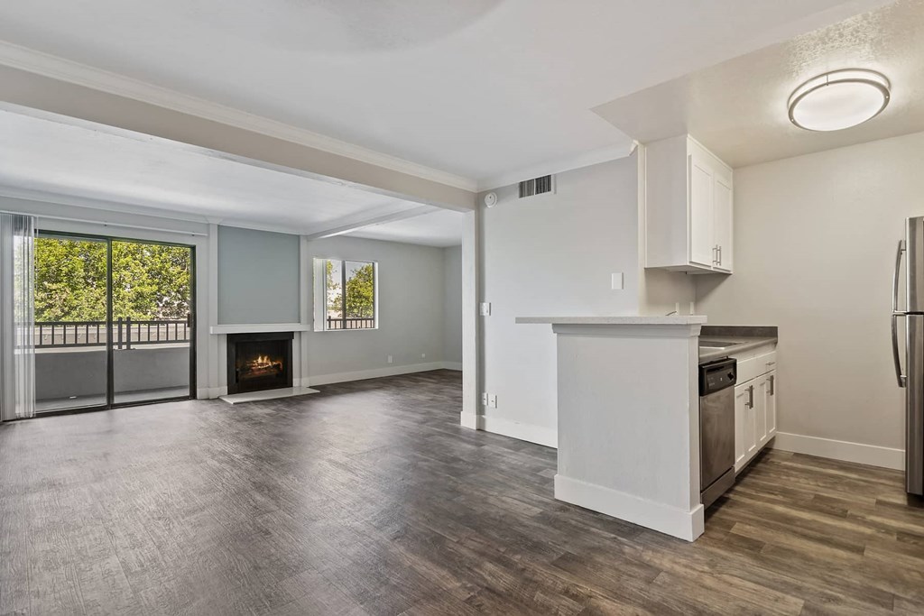 an empty living room with a kitchen and a fireplace