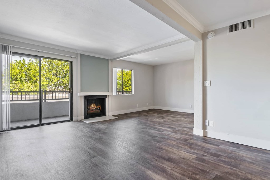 an empty living room with a fireplace and sliding glass doors